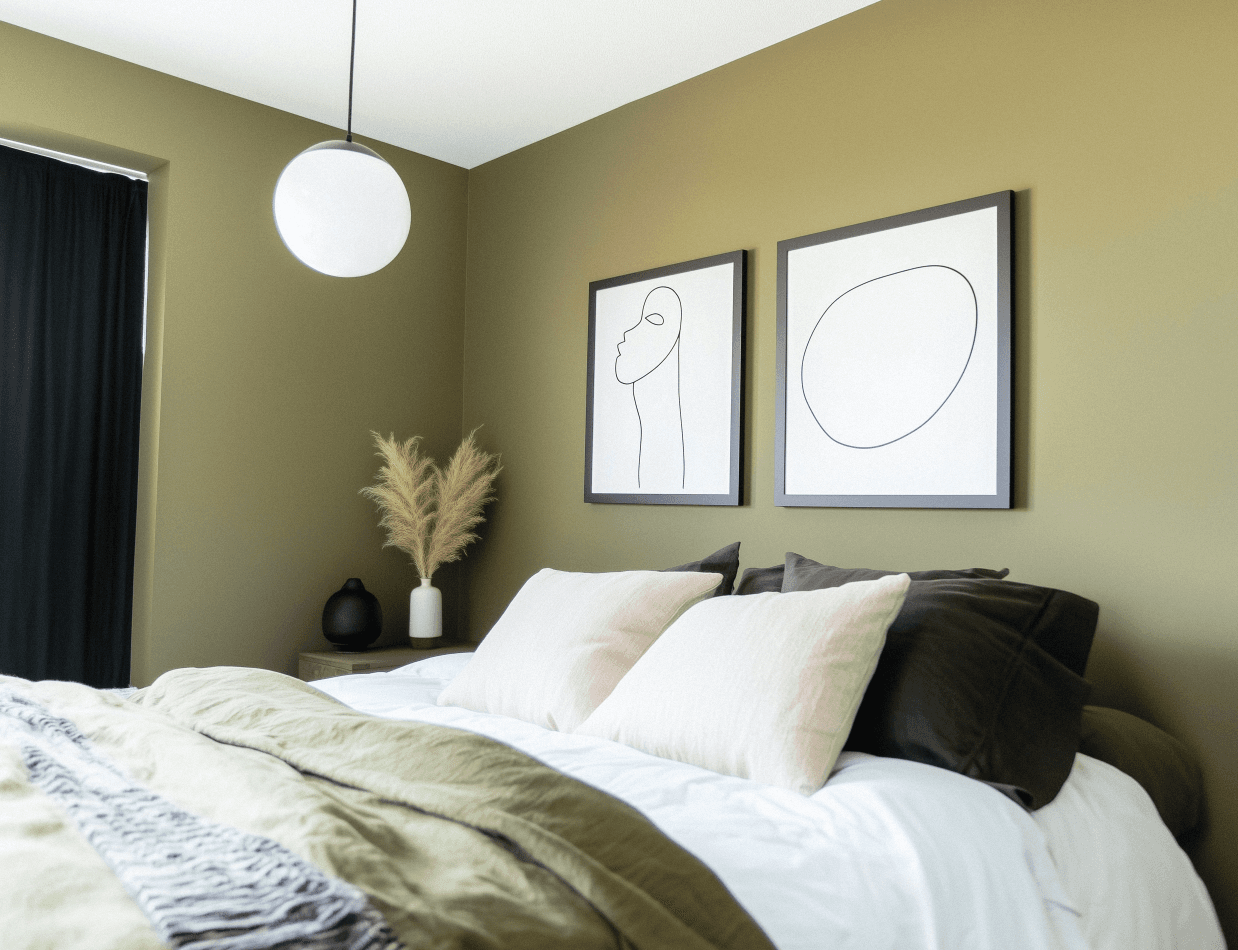 Modern bedroom with olive green walls, minimalist decor, line-up artistic paintings, comfortable bed with beige and green cushions, spherical pendant lighting.