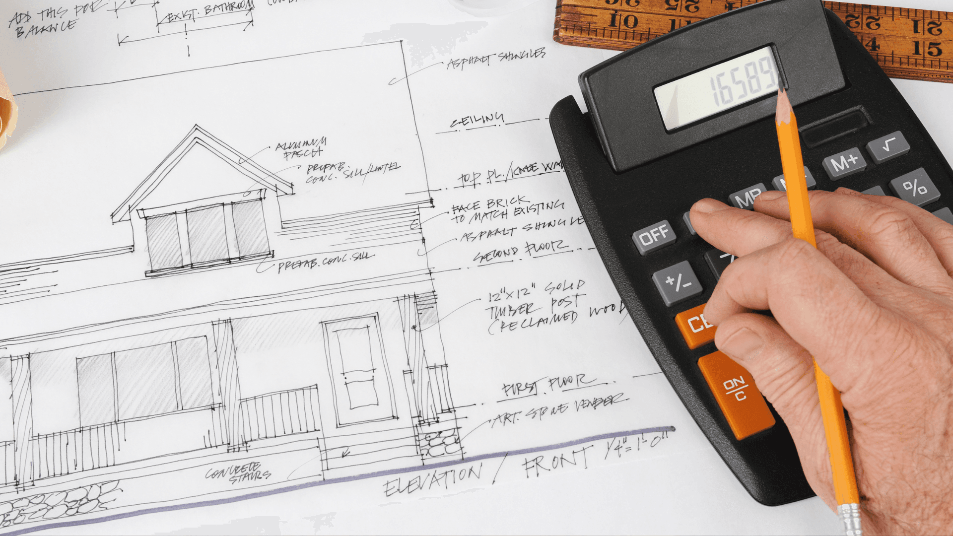 A detailed architectural plan of a house is spread out on a table, with annotations and measurements. A hand holding a pencil rests on a calculator, suggesting the calculation of project costs