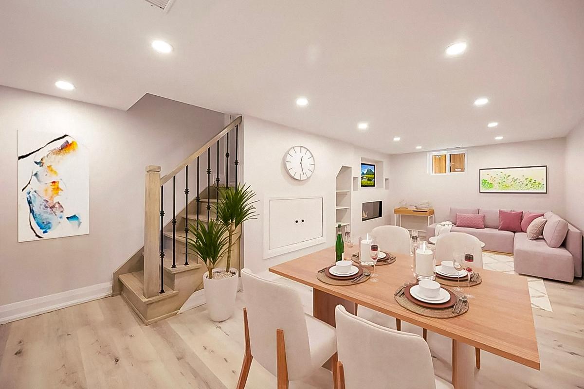 Finished basement with dining and living area, decorated in a modern style with a wooden staircase, white walls, and recessed lighting.