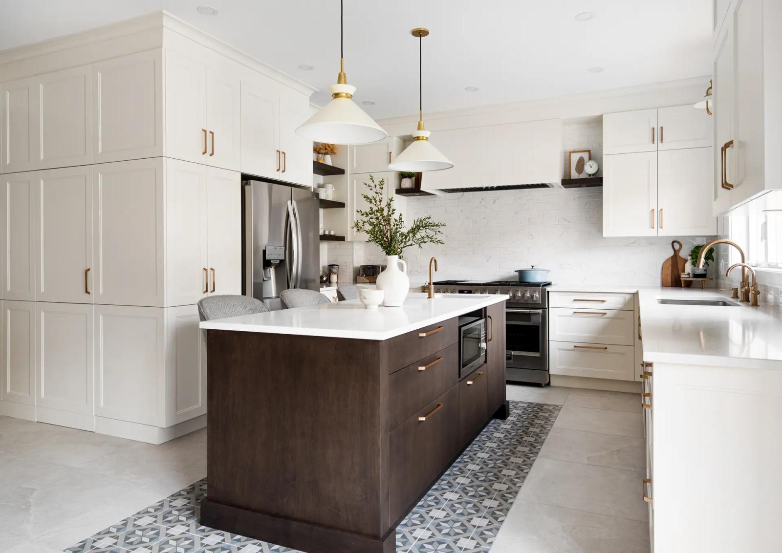 Transitional-style kitchen in Montreal, featuring a dark wood center island with warm drawers and a white quartz countertop. White shaker cabinets and gold handles add a touch of elegance to the space. The geometrically patterned ceramic tile floor adds a touch of sophistication.