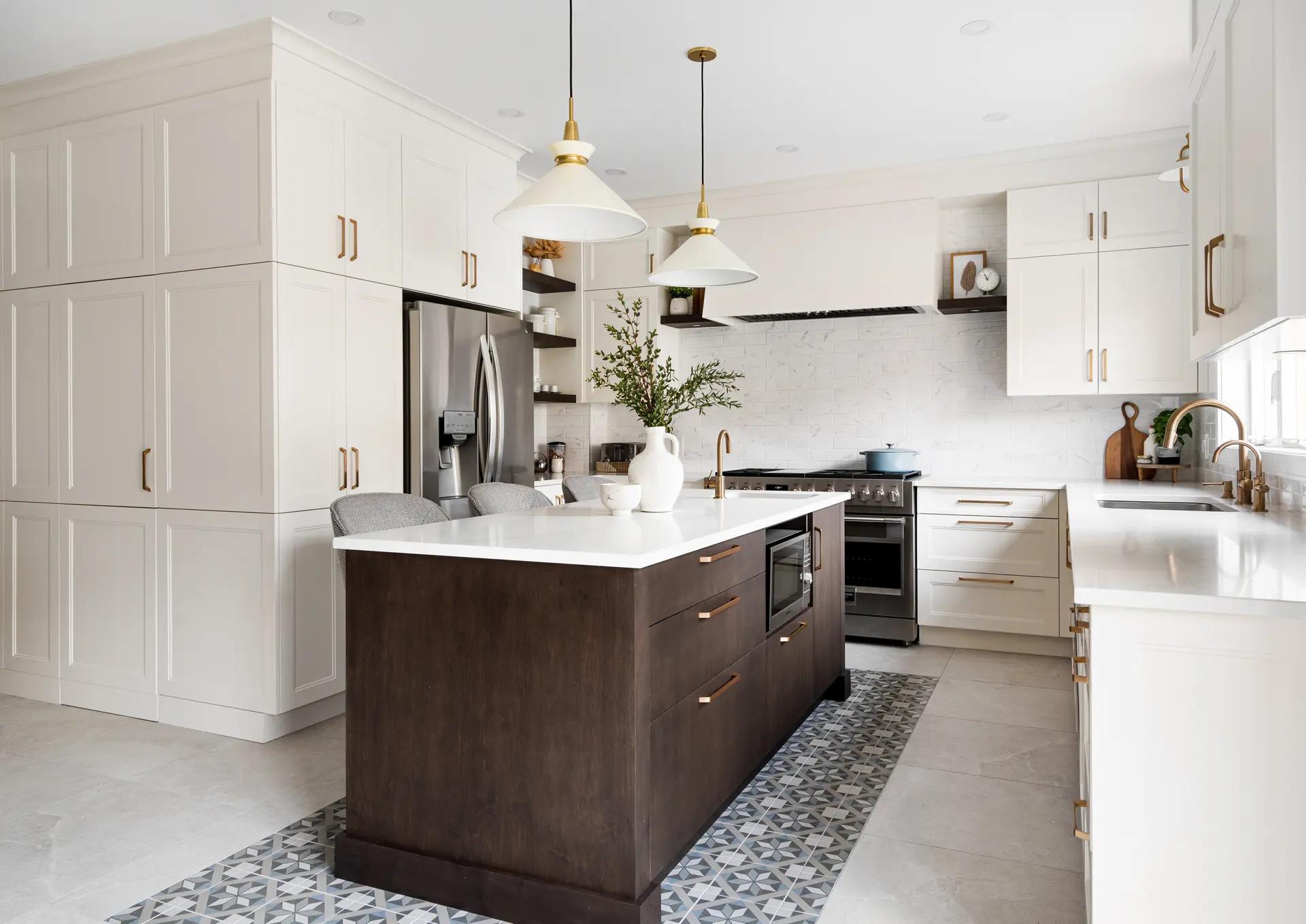 Transitional-style kitchen in Montreal, featuring a dark wood center island with warm drawers and a white quartz countertop. White shaker cabinets and gold handles add a touch of elegance to the space. The geometrically patterned ceramic tile floor adds a touch of sophistication.