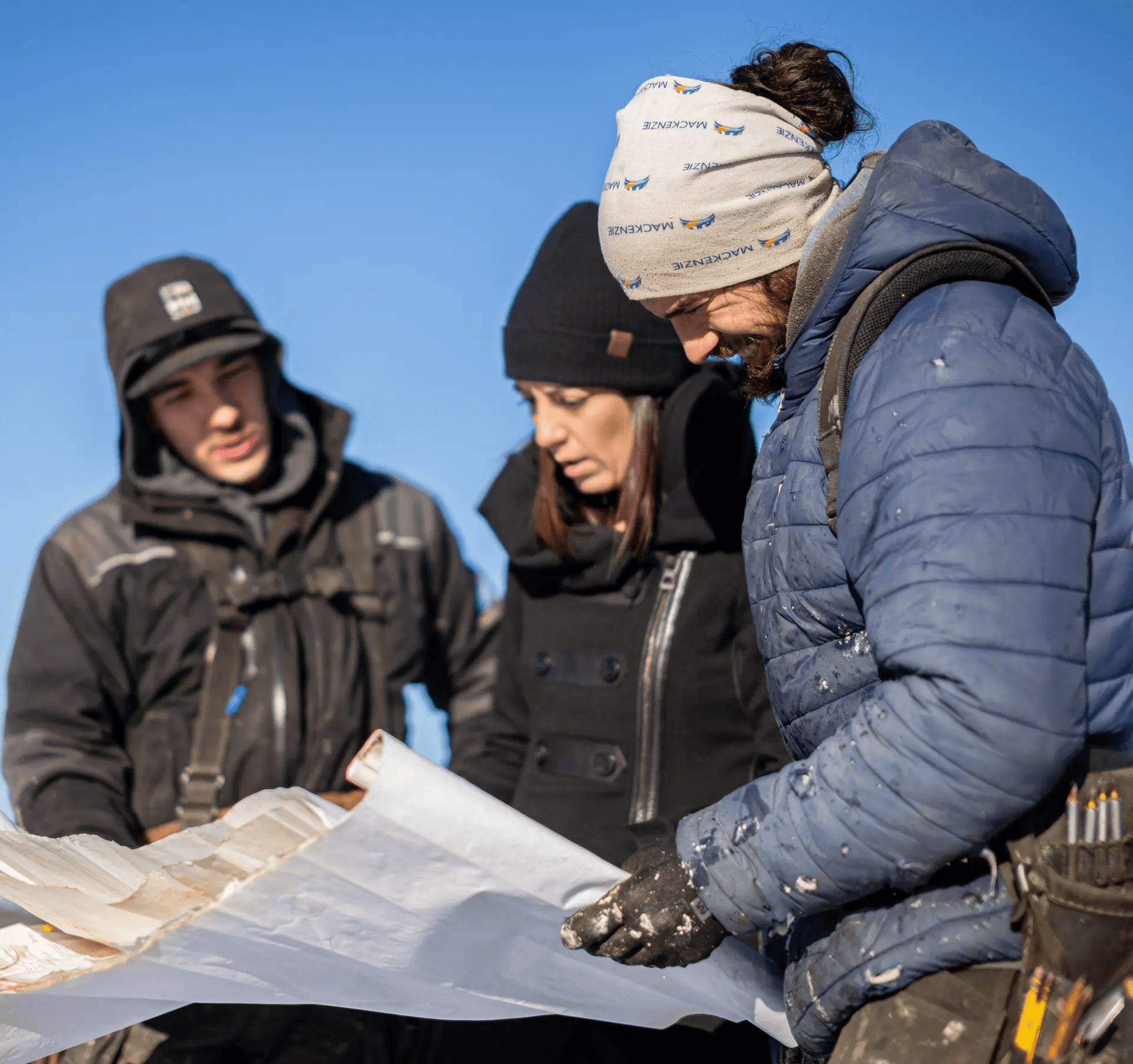 Team of construction professionals reviewing a site plan on a winter construction site.