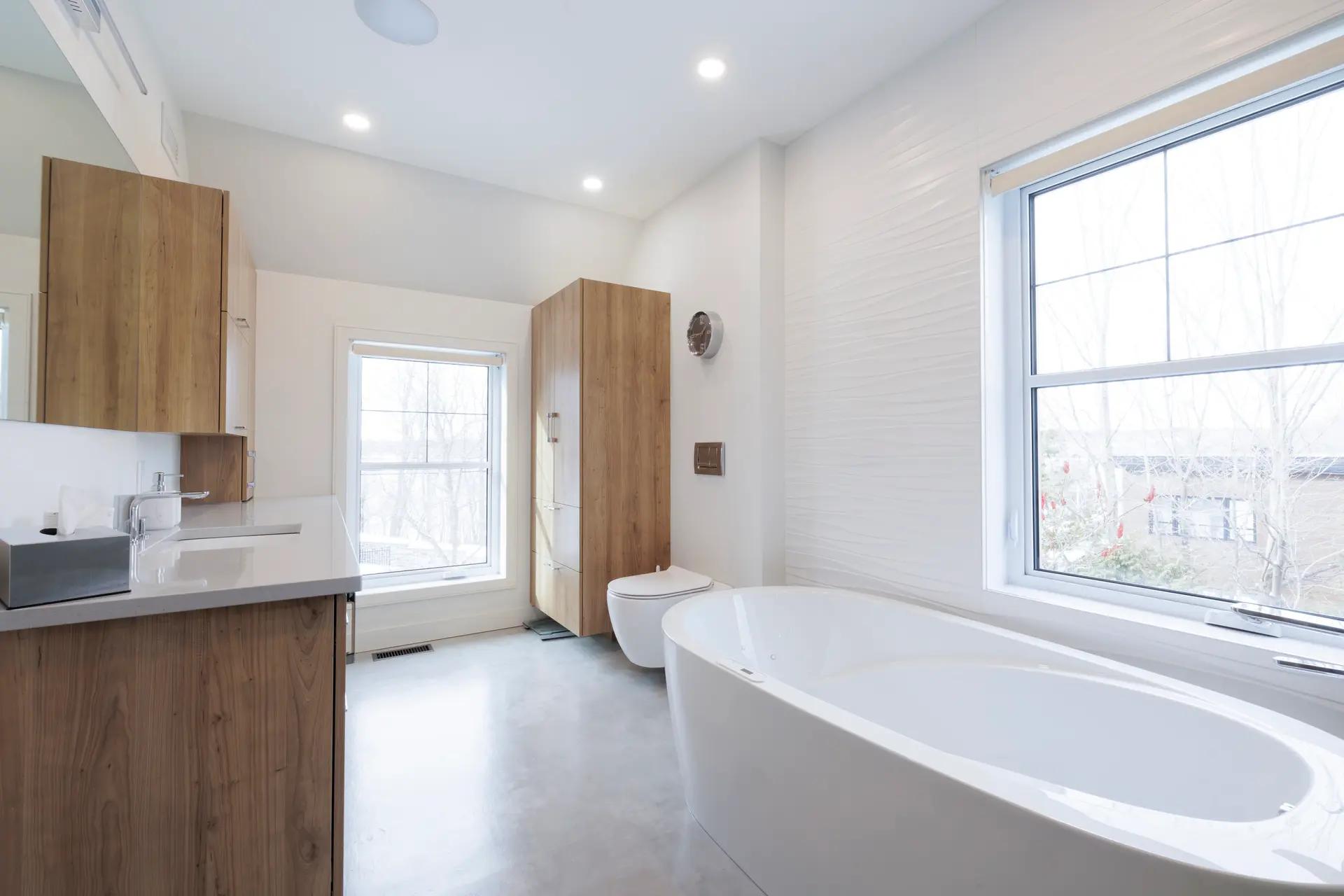 Modern and bright bathroom with a freestanding bathtub, wooden vanity, and white tiles