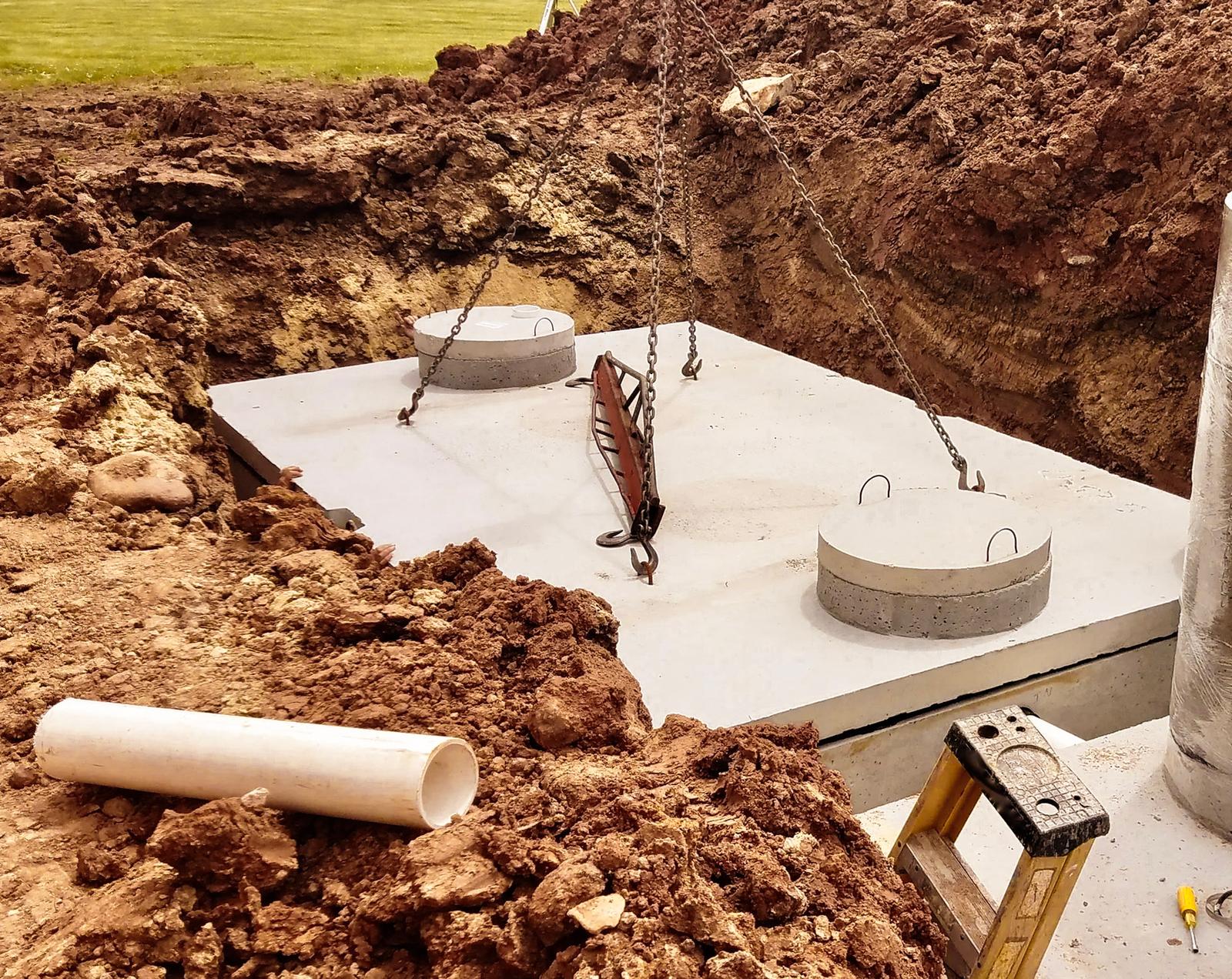Installation of a precast concrete septic tank with lifting chain.