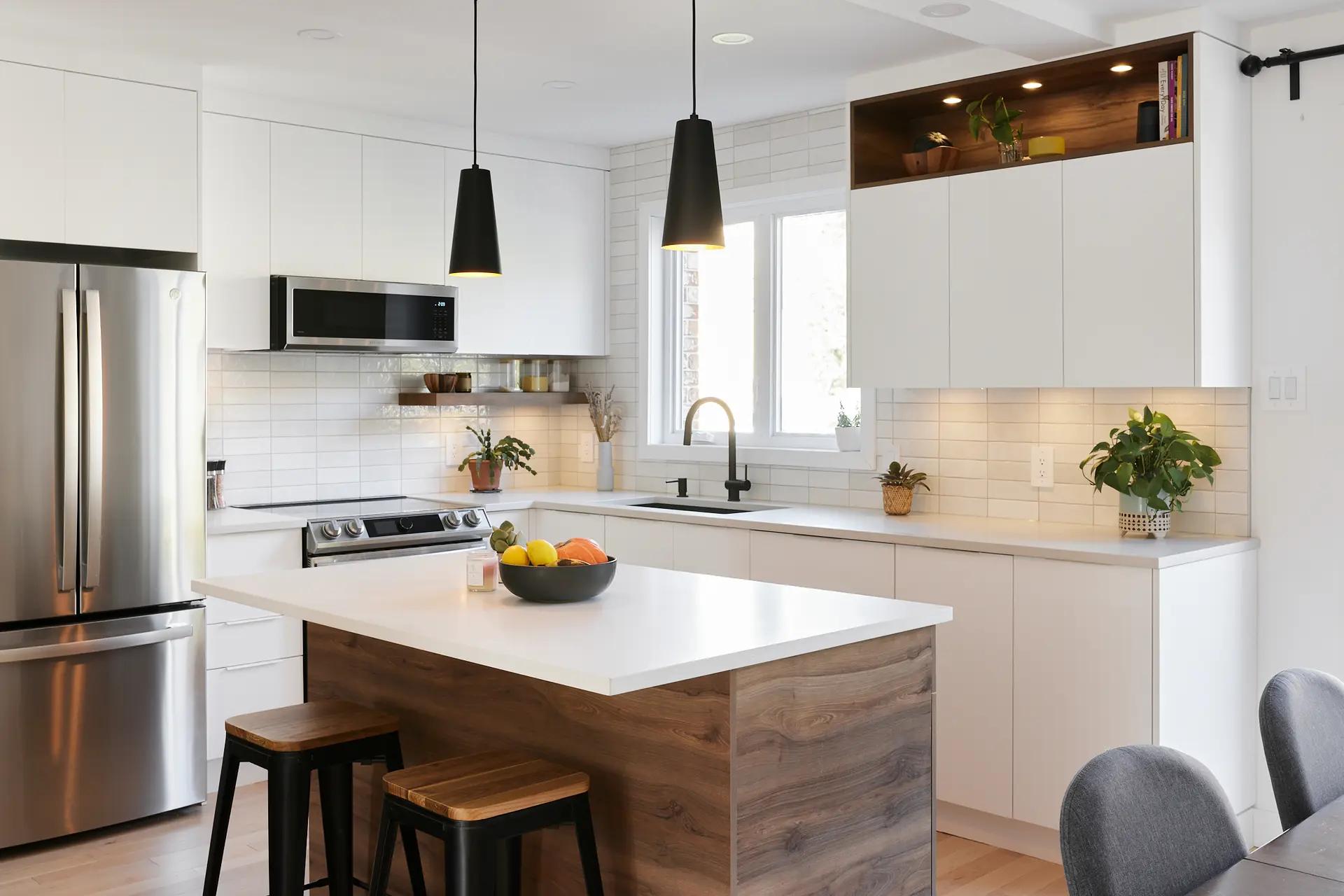 Scandinavian-style kitchen in Montreal, featuring a central island with natural wood countertop, minimalist white cabinetry and white subway tile backsplash. The light wood floor adds a touch of warmth to the space.