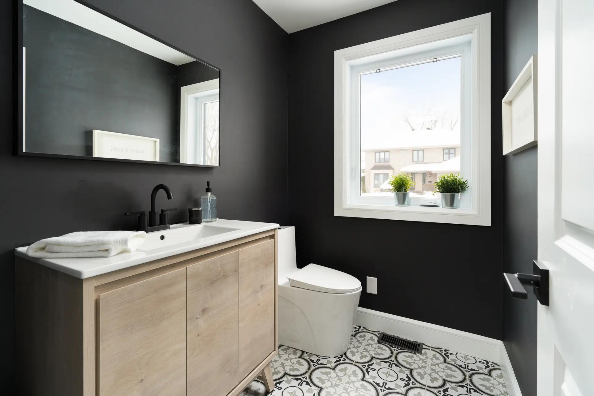 Contemporary bathroom interior with black walls, tiled floor, and a window providing natural light