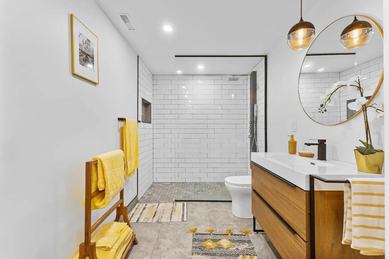 Bright bathroom with a walk-in shower surrounded by white subway tiles, a vessel sink on a wooden vanity, and a round mirror